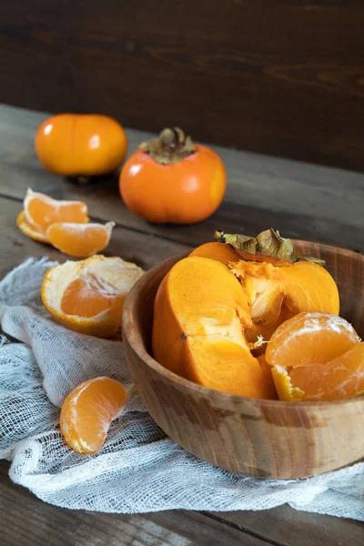 Caquis y mandarinas frescas en tazón —  Fotos de Stock