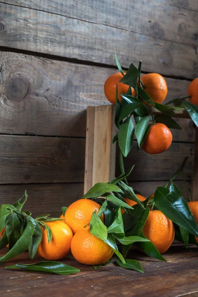 Tangerines with leaves on wooden box — Stock Photo, Image