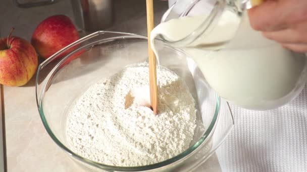 Pouring milk into flour. Whisking milk and flour in a glass bowl. Slow motion. — Stock Video