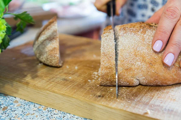 Woman cutting fresh homemade bread on wooden board