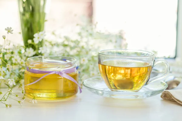 Miel en frascos de vidrio y taza de té —  Fotos de Stock