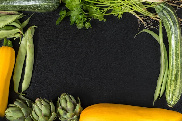 Свежие органические зеленые овощи на черном полу — стоковое фото