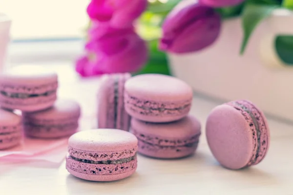 Violet sweet delicious macaroons and fresh tulips — Stock Photo, Image