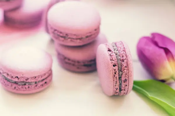 Violet sweet delicious macaroons and fresh tulips — Stock Photo, Image