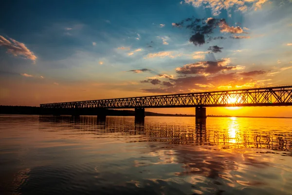 Приголомшливі кольори заходу сонця над річкою з мостом в літній вечір — стокове фото