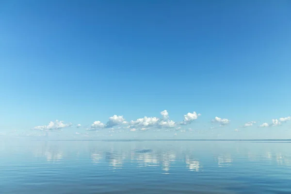 Блакитне небо зі світлими білими хмарами над поверхнею річки — стокове фото