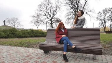 Kadın gençler smartphone cep telefonu ile kürsüye bir sonbahar Şehir Parkı içinde müzik dinlemek
