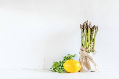 Demet taze kuşkonmaz küçük bir çuval, limon ve taze par