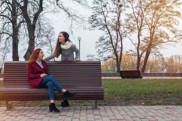 Kvinnliga tonåringar lyssnar på musik på smartphone på bänken — Stockfoto