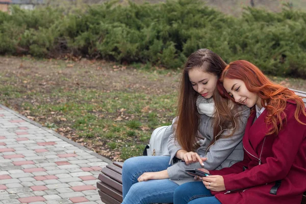 Жіночі підлітки слухають музику на смартфоні сидячи — стокове фото