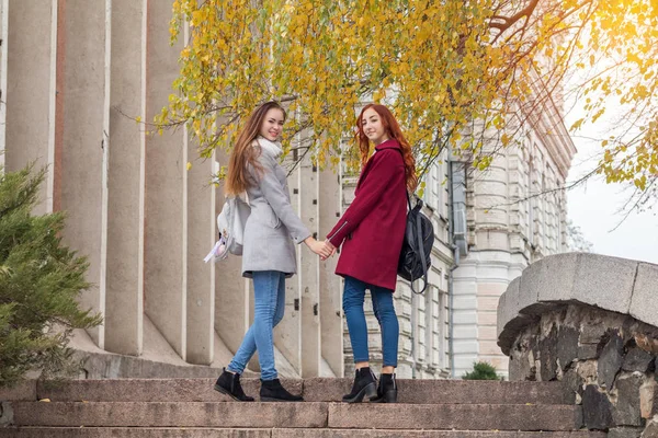 Two female teenagers walking up the stone steps holding hands in — Stock Photo, Image