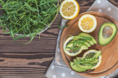 Çavdar ekmeği kesme avokado, roka ve limon yuvarlak tahta üzerinde