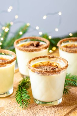 Noel ve kış tatillerinde tarçınlı yumurta likörü ve hindistan cevizi. Ahşap masa yüzeyinde gözlüklü ev yapımı eggnog, alanın sığ derinliği, kopyalama alanı.