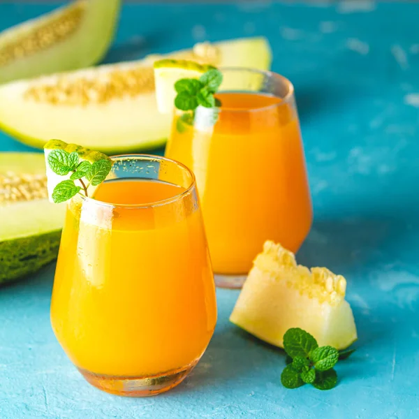 Yellow orange cocktail with melon and mint in glass on blue conc