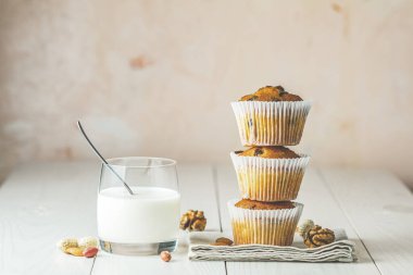 Kağıt bardakta vanilyalı karamelli kek ve beyaz bardakta süt.