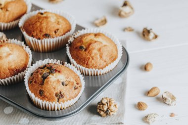 Beyaz ahşap zemin üzerinde kağıt bardaklarda vanilyalı karamelli kekler