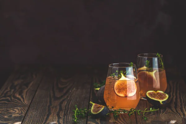 Rosa Cocktail mit Feige, Thymian und Eis im Glas auf dunklem Holzboden — Stockfoto