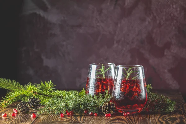 Dos vasos de bebida de granada rodeados de ramas de pino — Foto de Stock