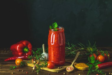 Ev yapımı Diy konserve sıcak domates sosu acı biberli ya da cam kavanozda, ahşap masada kiraz domatesli, tuzlu, biberli, şifalı otlu, seçici odaklı.