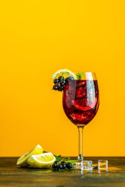 Siyah frenk üzümü, limon, nane ve buz sarı arka plan üzerinde uzun cam ile soğuk kırmızı kokteyl. Yaz içkileri ve alkollü kokteyller. Alkollü kokteyl Blackcurrant mojito