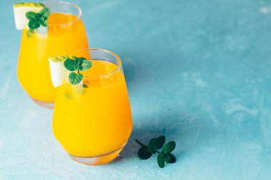 Sarı turuncu kokteyle kavun ve mavi beton arka planda nane şekeri, yakın plan. Yaz içkileri ve alkollü kokteyller. Alkolik ya da detoks kokteyli.