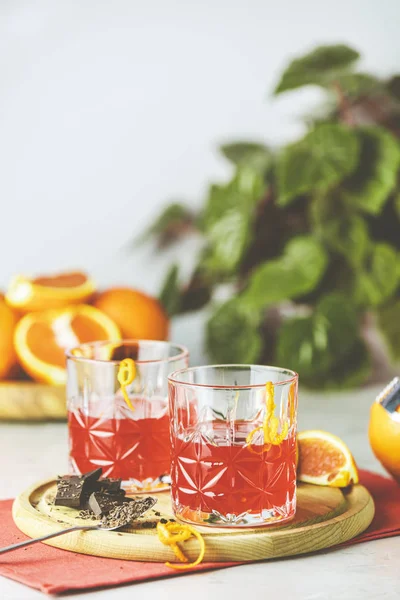 Two glasses of chocolate red orange negroni, an italian cocktail, an aperitif, first mixed in Firenze, Italy, in 1919, alcoholic bitter cocktail served by ingredients on the light gray table. — 스톡 사진