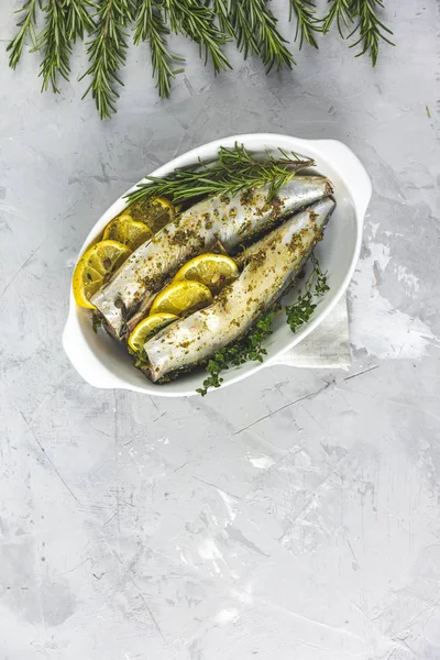 Mackerels servido em prato branco com limão, tomilho, alecrim e especiarias. Peixes marinados crus na superfície cinzenta clara. Fundo de marisco . — Fotografia de Stock