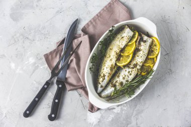 Uskumrular limon, kekik, biberiye ve baharatla servis edilir. Açık gri yüzeyde marine edilmiş çiğ balıklar. Deniz ürünleri arka planı.