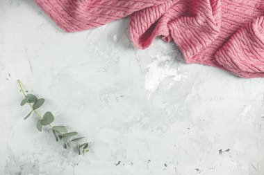 Pembe battaniye ve okaliptüs yapraklarından yapılmış çerçeve gri beton arka planda. Bahar konsepti Düz konum, üst görünüm, kopyalama alanı