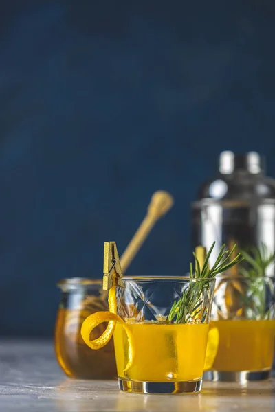 Два бокала медового коктейля с розмарином простой сироп или домашний коктейль виски кислый напиток с апельсиновой и розмариновой отделкой апельсиновой кожуры, банка меда и барменские инструменты — стоковое фото