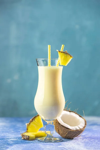 Lezzetli bir bardak donmuş Pina Colada geleneksel Karayip kokteyli. Bir dilim ananas ile süslenmiş, mavi beton arka planda servis ediliyor..