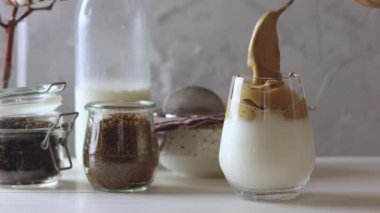 Kadın eli buzlu köpüklü içeceğe Dalgona Kahvesi ekliyor. Trend Kore kahveli latte espresso içer. Açık kırsal biçim.
