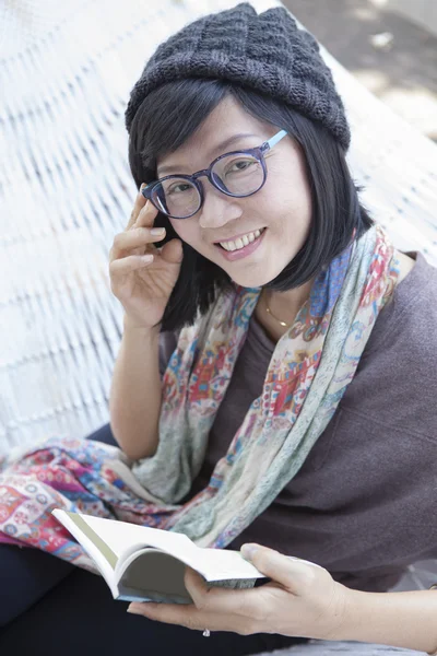 Asian woman and pocket book in hand relaxing on home cradle — Stock Photo, Image