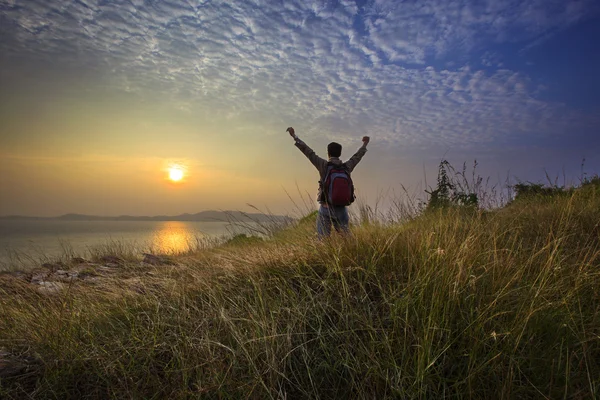 Trekker man rising victory hand at nature trail with sun set sky — Stock Photo, Image