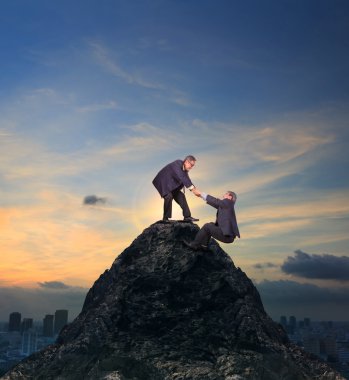 two of asian business man helping hand to climbing up to peak of clipart