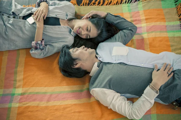 Par av yngre asiatiska manen och kvinnan avslappnande känsla liggande i — Stockfoto