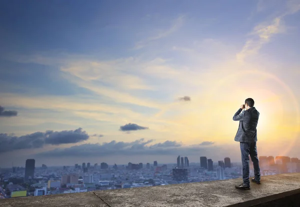 Hombre de negocios y espionaje binocular en la parte superior del edificio wiht urbano — Foto de Stock