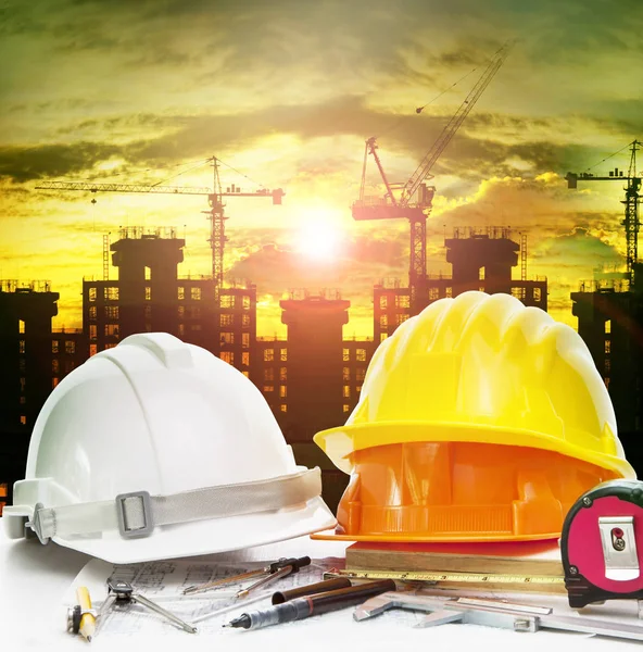 Safety helmet on engineer working table and construction site ba — Stock Photo, Image