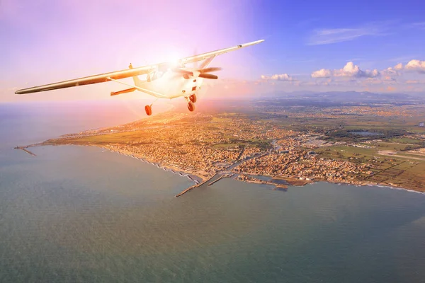 Avión de hélice volando sobre la costa de la luz del sol de remolque detrás —  Fotos de Stock