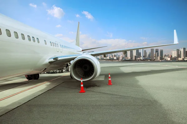 Passagierflugzeug parkt auf Landebahn des Flughafens mit städtischem Hintergrund — Stockfoto