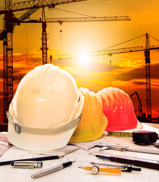 safety helmet on engineer working table and construction site background