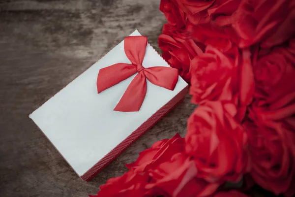 Caja de regalo de San Valentín en mesa de madera con ramo de rosas rojas para el amor — Foto de Stock