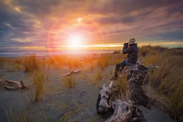 Photographer taking a sunset photo on sea beach — Stock Photo, Image