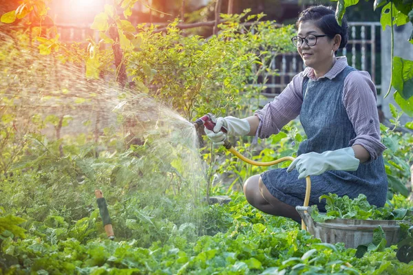 Asian woman relaxing and watering in home garden — Stock Photo, Image