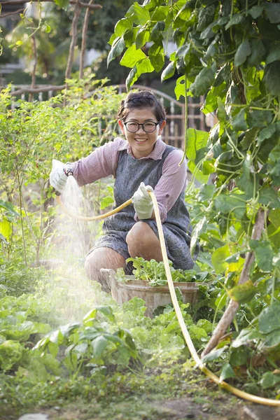 Aziatische vrouw ontspannen water gieten in huis moestuin — Stockfoto