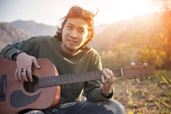 亚洲年轻男人放松户外用旧的吉他，为人 l — 图库照片
