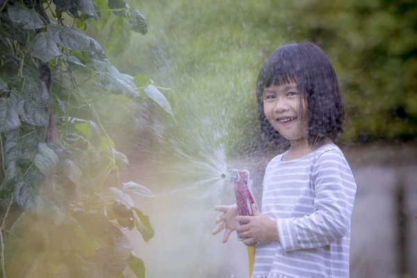 Asiatiska barn spelar vatten stänk frome en slang med happine — Stockfoto