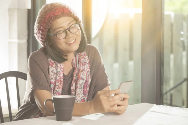 Woman and smarthphone in hand sitting in coffee shop against european building scene — Stock Photo, Image