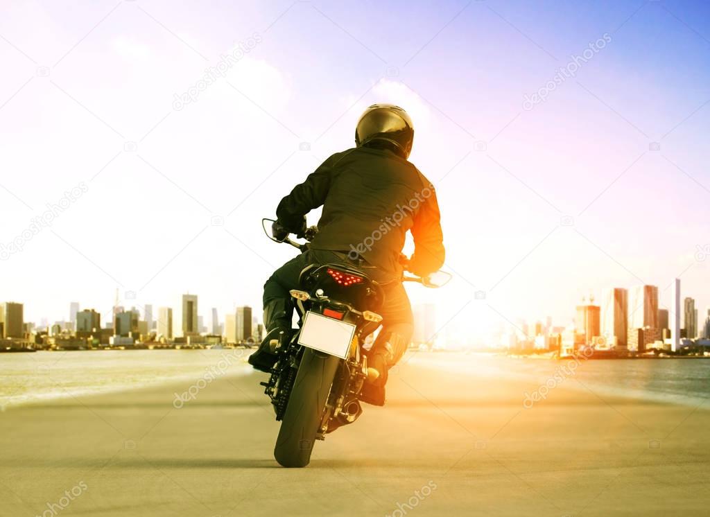 rear view of man riding motorcycle on urban traffic road for peo