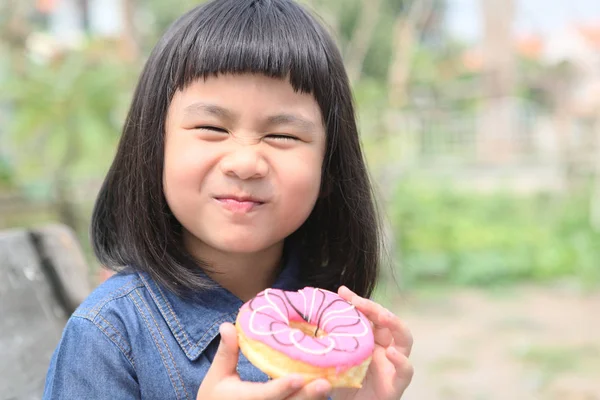Щасливе обличчя азіатських дітей з солодким пончиком в руці — стокове фото